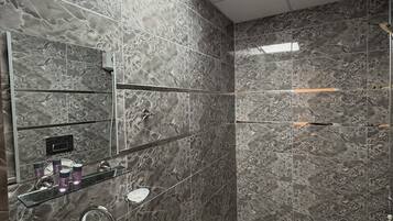 Ein modernes Badezimmer mit großem Spiegel, Waschbecken, Dusche und Toilette.