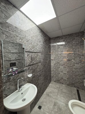 A modern bathroom with a large mirror, a sink, a shower, and a toilet. - Kerem dalgıç suit (Adana)