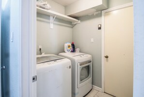 Un cuarto de lavandería con lavadora, secadora y detergente.