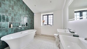 Een moderne badkamer met een vrijstaand bad, een wastafel met spiegel, en een raam met uitzicht.