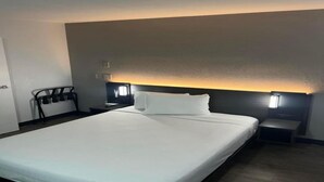 Ein Hotelzimmer mit einem großen Bett, Nachttischen, einer Kopfstütze mit integrierter Beleuchtung und Meerblick.