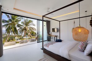 Een moderne slaapkamer met een groot bed, een bureau en een balkon met palmbomen.
