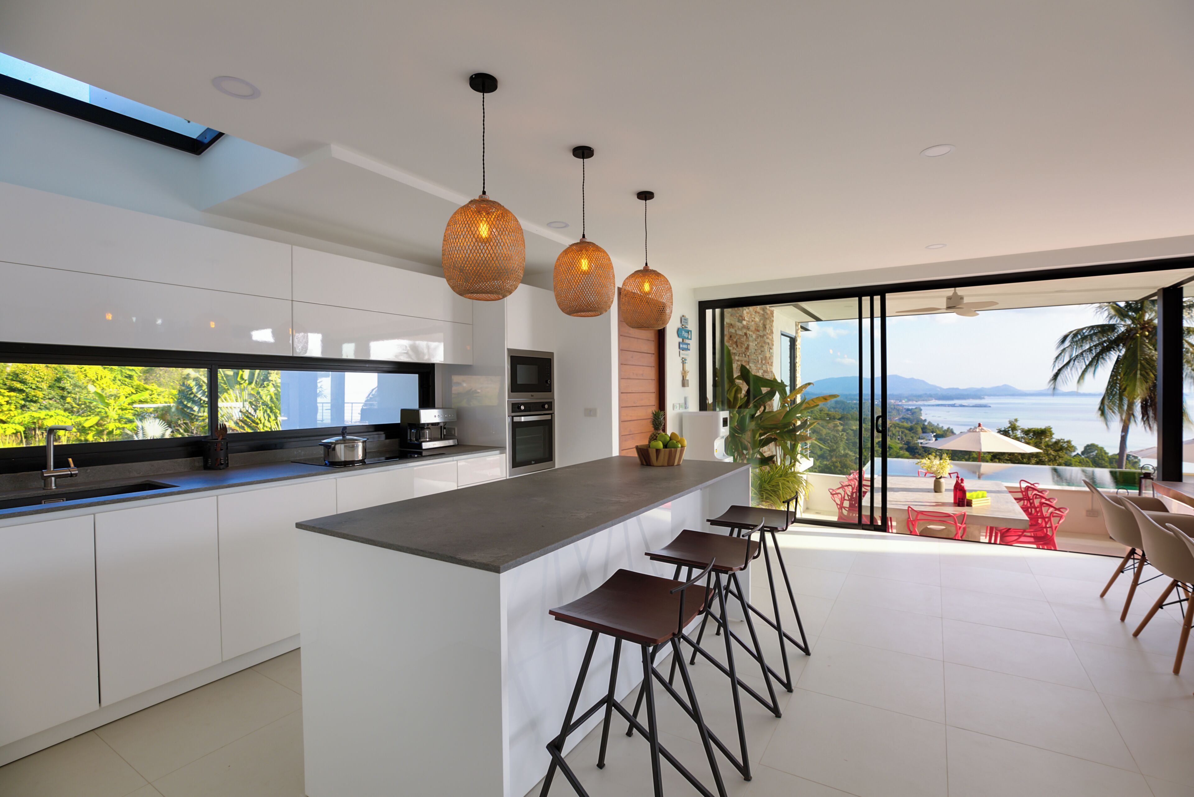 A modern kitchen with a large island, bar stools, and a view of the ocean.