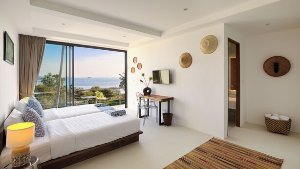 A modern bedroom with a large bed, a desk, and a television.