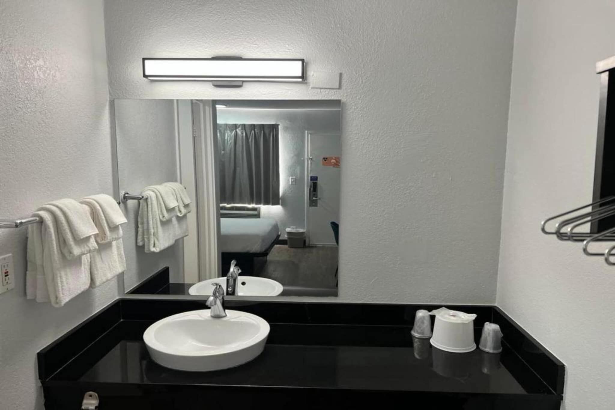 Un baño moderno con un espejo grande, un lavamanos y un perchero para toallas.