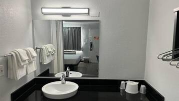Un baño moderno con un espejo grande, un lavamanos y un perchero para toallas.