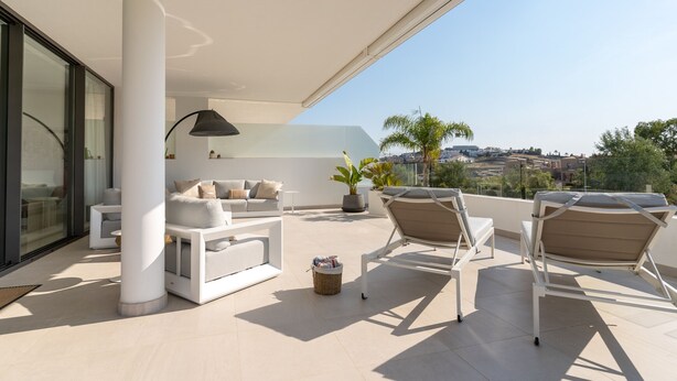 Un espacio exterior moderno con sofá, sillones y una lámpara.