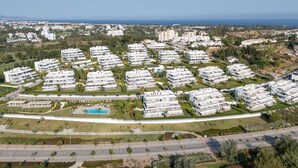 Zona residencial con edificios de apartamentos modernos, una piscina y una calle.