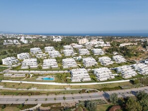 A residential area with modern apartment buildings, a swimming pool, and a road. - Cateleya Residence by Time & Home (Estepona)