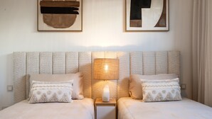 Una cama doble con un cabecero con textura, dos mesitas de noche con lámparas y almohadones decorativos.