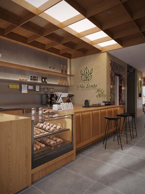 A bakery interior with a wooden counter, a display case with pastries, and a coffee machine. - D'la Lento Hotel (Hanoi)