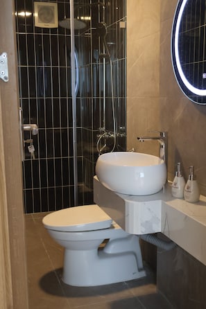 Un baño moderno con inodoro, lavamanos y ducha.