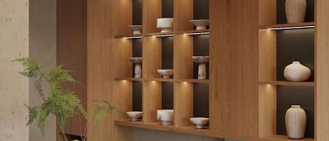 A modern kitchen with wooden cabinetry, built-in shelves, and a central island with a kettle and cups.