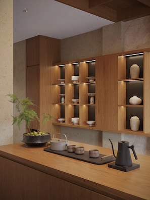 Una cocina moderna con armarios de madera, estantes empotrados y una isla central con un hervidor y tazas.
