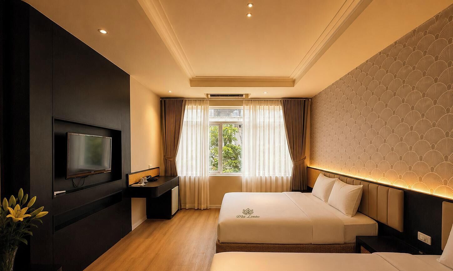 A hotel room with a bed, a television, a desk, and a window with curtains.
