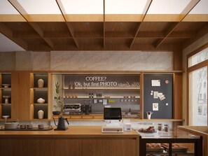 Interior de una cafetería con mostrador de madera, máquina de espresso y diversos artículos relacionados con el café.