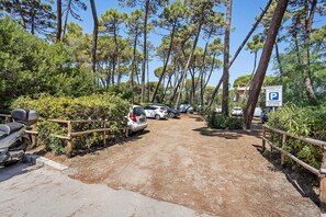 Ein Parkplatz mit mehreren Autos, einem Holzzaun und einem Schild, das einen Stellplatz für einen bestimmten Ort kennzeichnet.