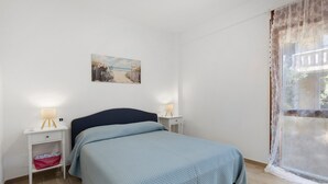 A bedroom with a bed, bedside tables, a lamp, and a painting on the wall. - Holiday Home 'Baby' with Private Terrace, Wi-Fi and Air Conditioning (Principina a Mare)