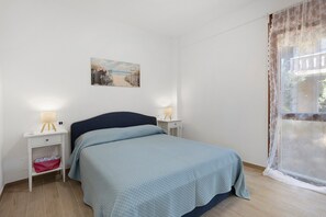 Ein Schlafzimmer mit einem Bett, Nachttischen, einer Lampe und einem Bild an der Wand.