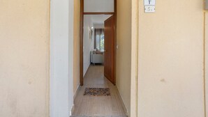 A narrow hallway with a wooden door at the end, a doormat, and a wall-mounted sign indicating the location. - Holiday Home 'Baby' with Private Terrace, Wi-Fi and Air Conditioning (Principina a Mare)