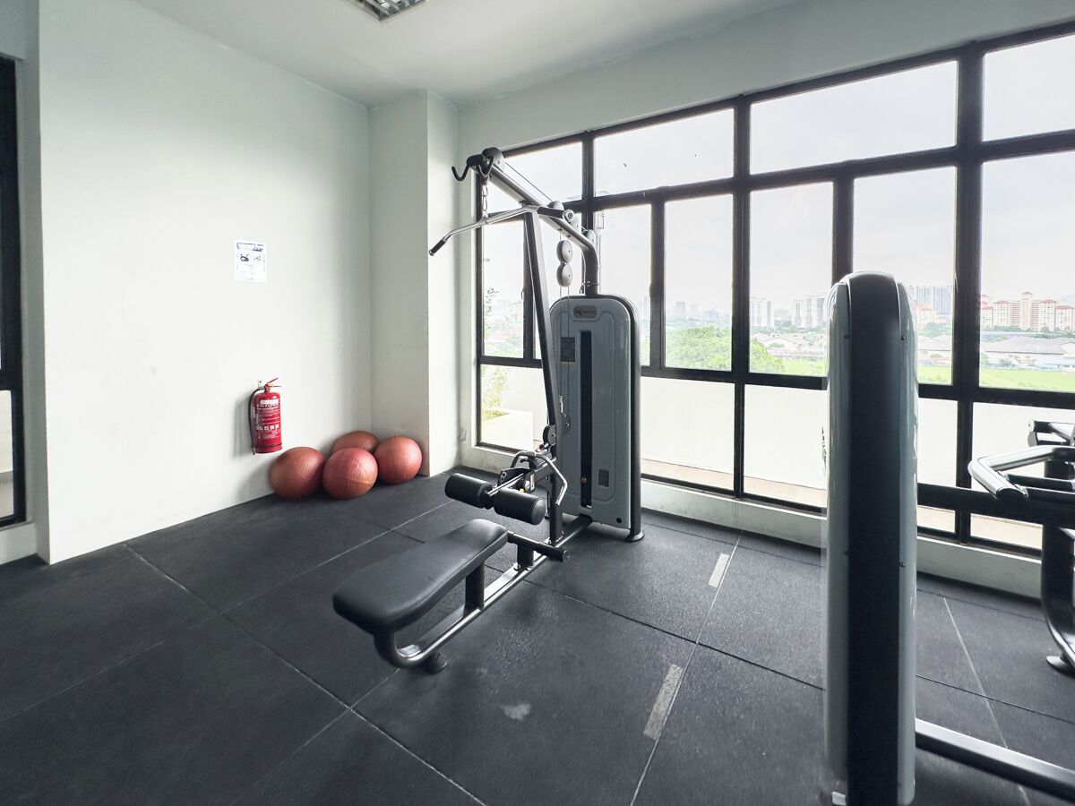 Ein Fitnessraum mit Trainingsgeräten, einem Feuerlöscher und Übungsbällen.
