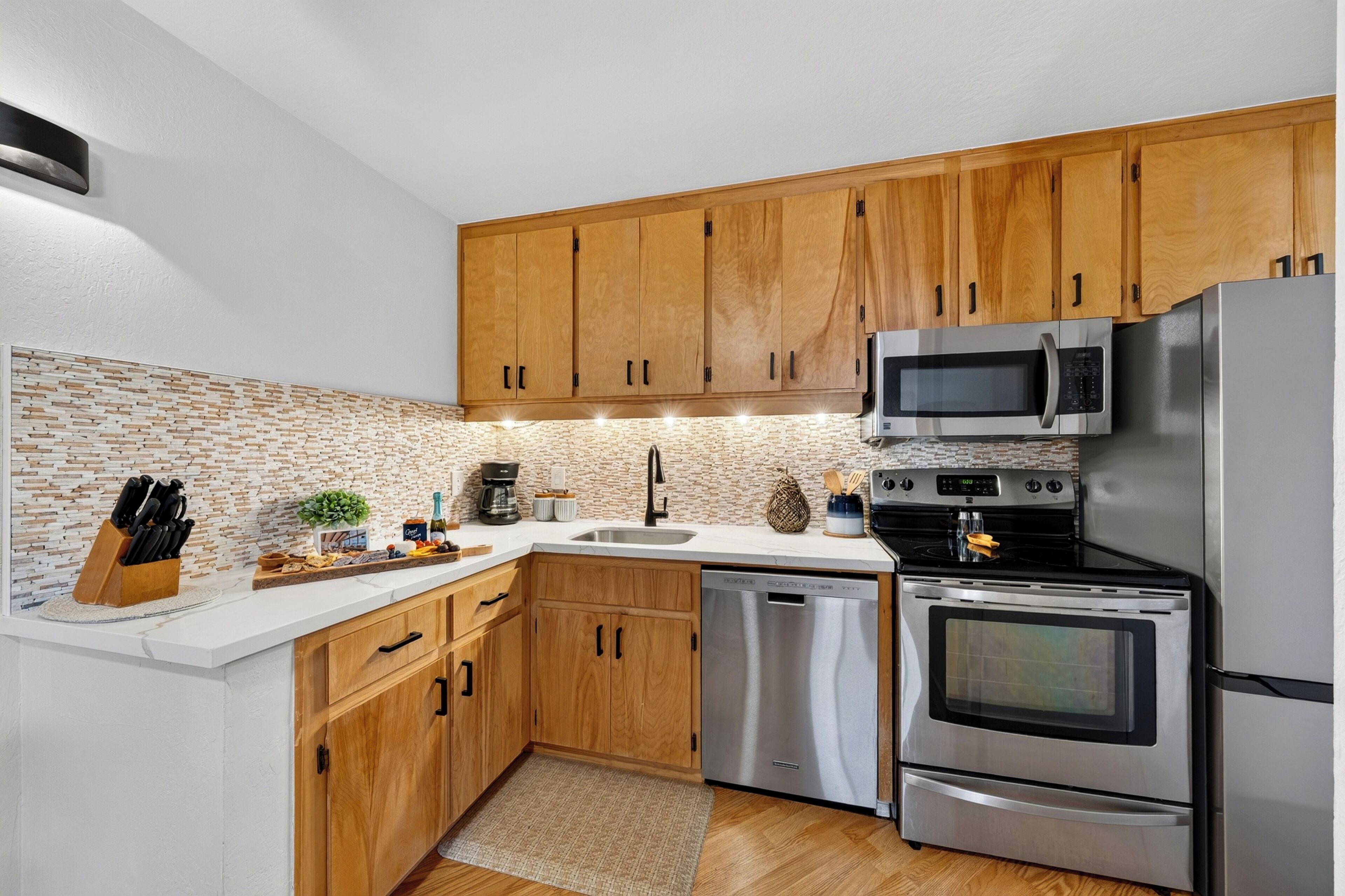 Una cucina moderna con mobili in legno, elettrodomestici in acciaio inossidabile e una parete di fondo in pietra.