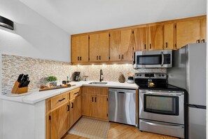 Eine moderne Küche mit Holzschränken, Edelstahlgeräten und einer Stein-Spritzschutzwand.