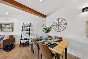 A dining area with a wooden table, chairs, a vase with a plant, a wall clock, and a decorative metal piece. - Private Boat Dock + BBQ Patio | Tahoe Keys Waterfront | Dock & Pine (South Lake Tahoe)