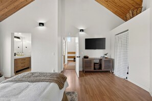 A bedroom with a bed, a dresser, a TV, and a window with blinds.