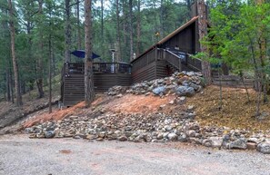 A cabin with a wooden exterior, a balcony, and a staircase leading to the upper level. - Mountain Views - Hot Tub - Dog Run - Sleeps 6 (Ruidoso)
