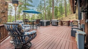 Una terraza con mobiliario exterior, una parrilla y una sombrilla azul.