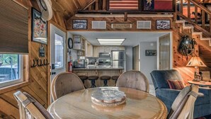Un interior de madera con una mesa de comedor, sillas, una zona de cocina y una escalera.