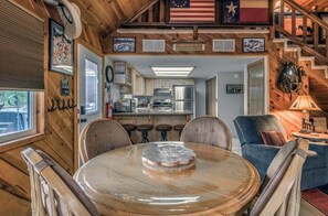 A wooden interior with a dining table, chairs, a kitchen area, and a staircase. - Mountain Views - Hot Tub - Dog Run - Sleeps 6 (Ruidoso)