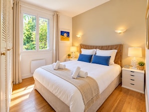 A well-lit bedroom with a large bed, two bedside tables, a window with curtains, and a wall-mounted artwork. - Pichilemu - Beach Access - Trouville-sur-Mer (Trouville-sur-Mer)
