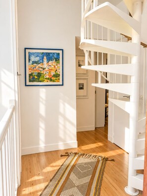 A staircase with white railings leading to an upper floor, a framed painting on the wall, and a patterned rug on the floor. - Pichilemu - Beach Access - Trouville-sur-Mer (Trouville-sur-Mer)