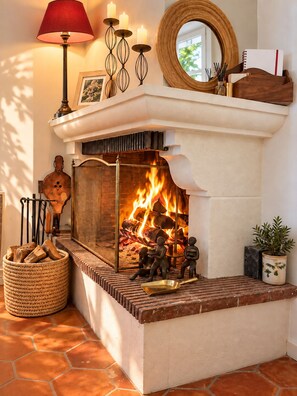 A fireplace with a fire, surrounded by decorative items and a mirror. - Pichilemu - Beach Access - Trouville-sur-Mer (Trouville-sur-Mer)