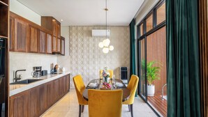 Una cocina moderna con armarios de madera, una mesa de comedor para cuatro personas y un amplio ventanal con cortinas.