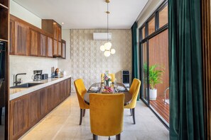Una cocina moderna con armarios de madera, una mesa de comedor para cuatro personas y un amplio ventanal con cortinas.