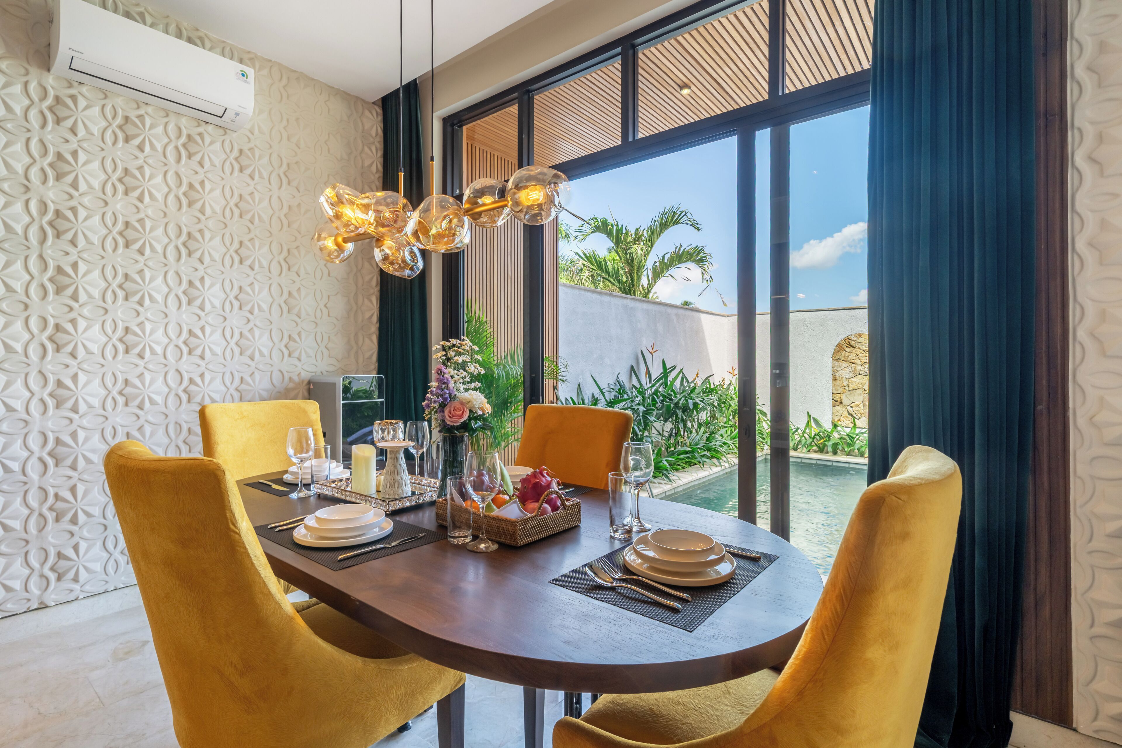 A dining area with a table set for four, a decorative light fixture, and a view of the outdoors.