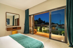 A bedroom with a bed, a mirror, a nightstand, and a view of a garden through a sliding glass door. - Sunny Villas Ubud (Gianyar)