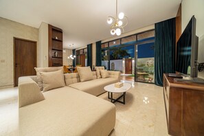 A modern living room with a sectional sofa, a coffee table, and a TV stand. - Sunny Villas Ubud (Gianyar)