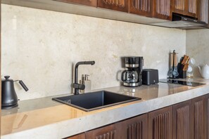 A kitchen with a modern sink, a coffee maker, and a kettle on the countertop. - Sunny Villas Ubud (Gianyar)