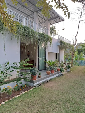 A modern house with a covered porch, potted plants, and a well-maintained lawn.
