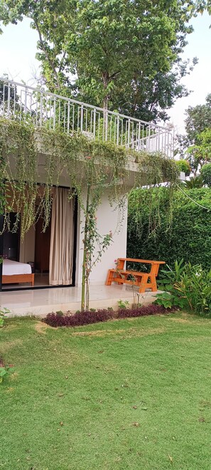 Una casa moderna amb un balcó, un llit i un petit jardí.