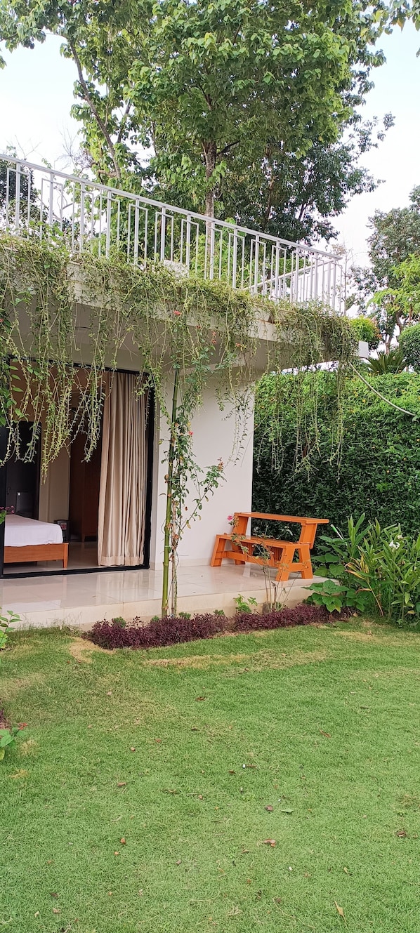 A modern house with a balcony, a bed, and a small garden area.
