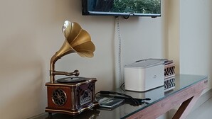 A room with a wooden desk, a gramophone, a television, and a clock on the wall. - you can enjoy the mountains, rivers greenery & modern luxury resort together. (Rangamati)
