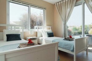 A hotel room with two beds, a window, a nightstand, and a view of the outdoors. - 3BR Panoramic Sea View Villa with Private Pool (Pissouri)