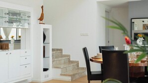 A modern interior with a dining area, a staircase, and a kitchen with glass cabinets. - 3BR Panoramic Sea View Villa with Private Pool (Pissouri)