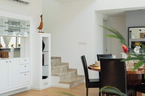 A modern interior with a dining area, a staircase, and a kitchen with glass cabinets.