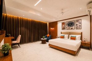 A modern hotel room with a large bed, a desk, a chair, and a small table. - Aarambh by The Sky Imperial Jamnagar (Jamnagar)